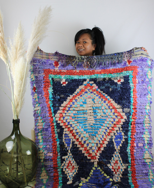 Gérante de Cel'souk qui tient un tapis marocain artisanal dans les mains